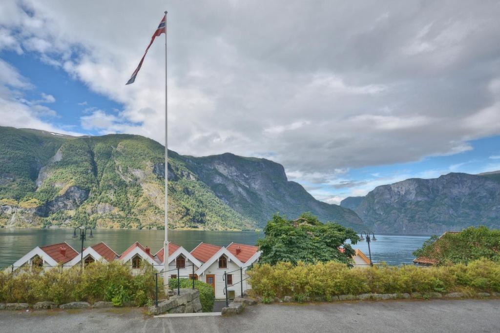 a row of houses in front of a lake with mountains at Vangsgaarden Gjestgiveri in Aurland