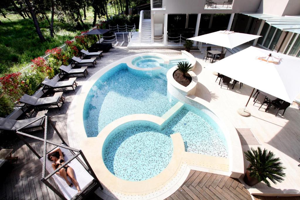 einen Blick über einen Pool mit Stühlen und Sonnenschirmen in der Unterkunft Hotel Stella Della Versilia in Marina di Massa