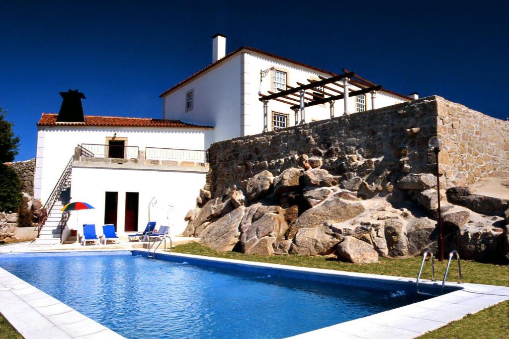 une maison avec une piscine en face d'un bâtiment dans l'établissement Solar dos Caldeira e Bourbon, à Zebras