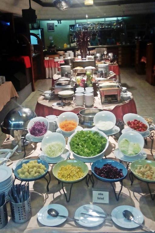 A buffet station with salad ingredients, bowls, plates and serving utensils.