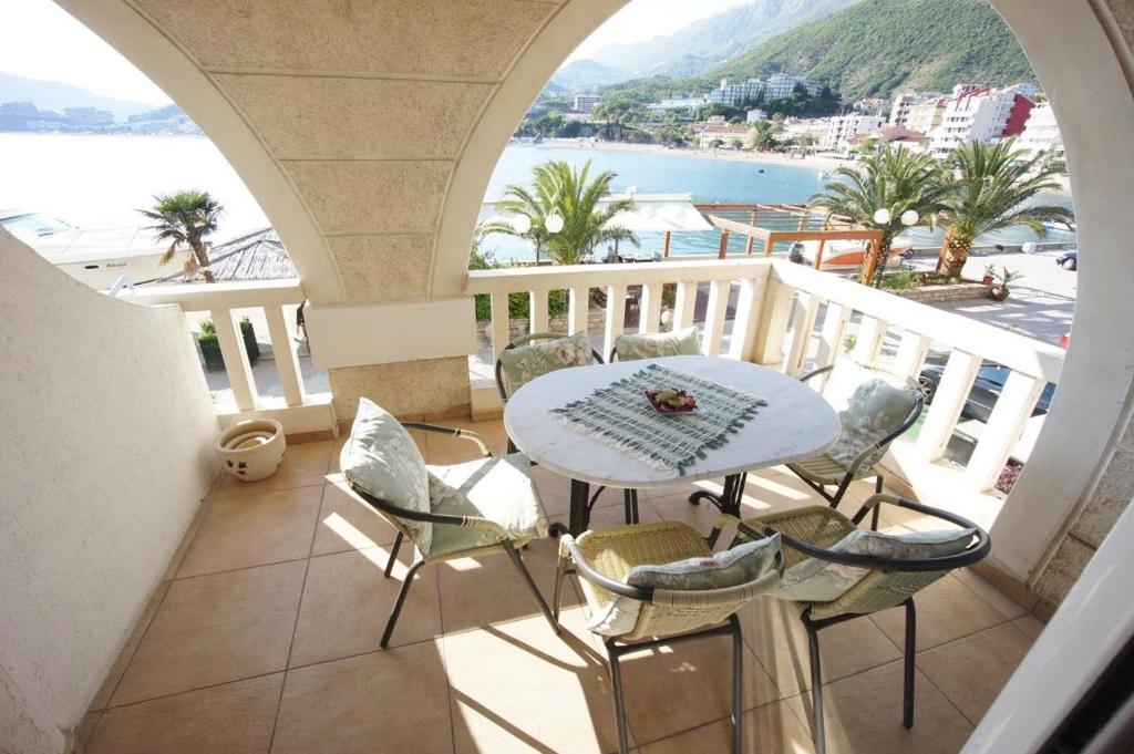 balcón con mesa, sillas y vistas al océano en Apartman Beauty, en Rafailovici