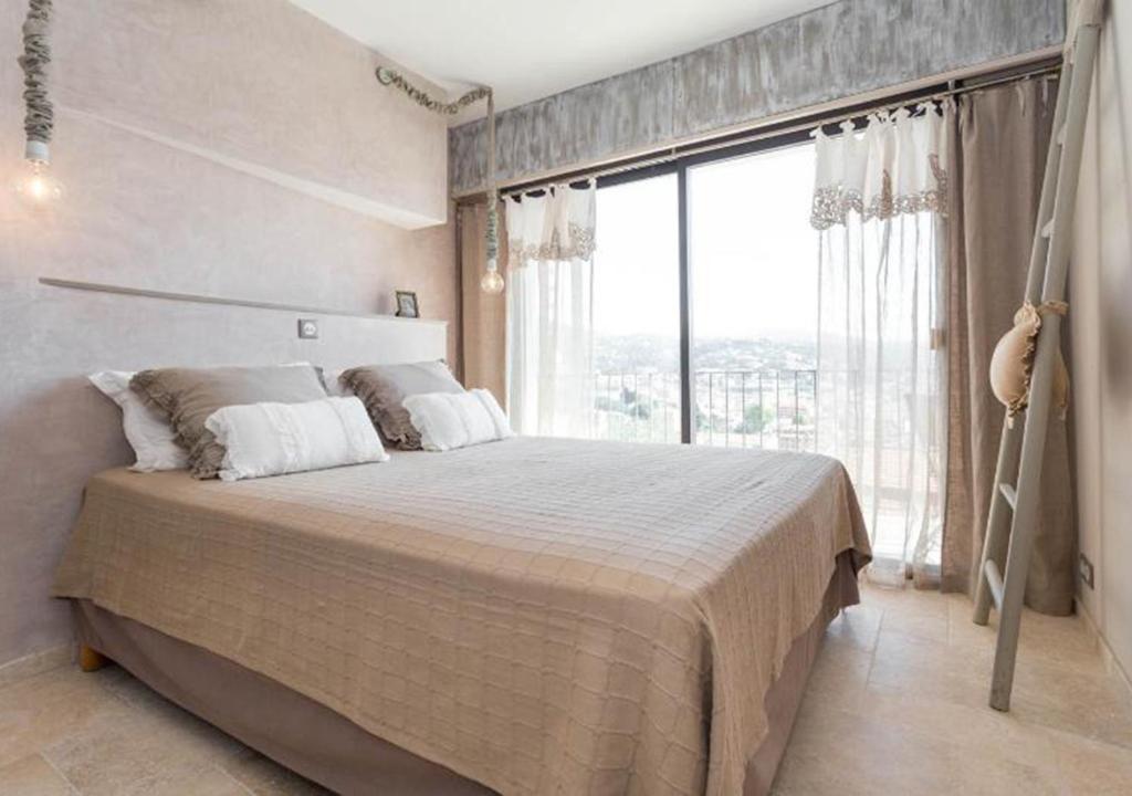 une chambre avec un grand lit avec une grande fenêtre dans l'établissement La maison de lulu, à Nice
