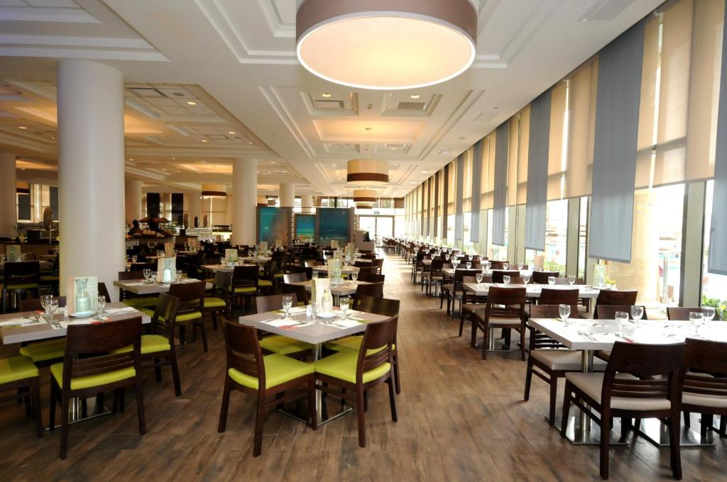 ein Esszimmer mit Tischen und Stühlen und Fenstern in der Unterkunft U Magic Palace in Eilat