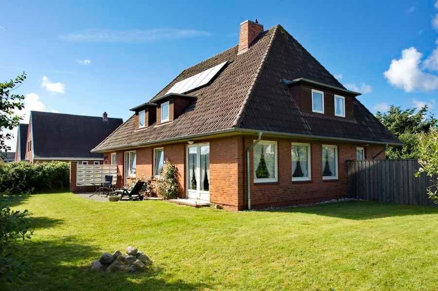 una pequeña casa con un césped verde delante de ella en Haus Penny Sylt, en Wenningstedt