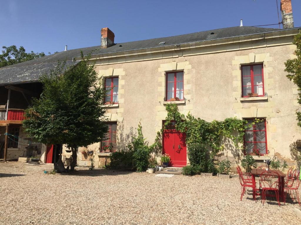 una casa antigua con puerta roja y sillas rojas en Aux Caprices des Dieux, en Marnes