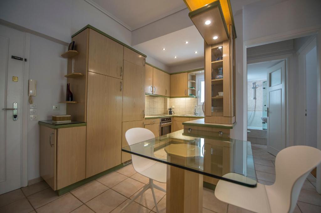 uma cozinha com uma mesa de vidro e cadeiras brancas em Starapartment Athens-Varkiza Top 2 em Varkiza