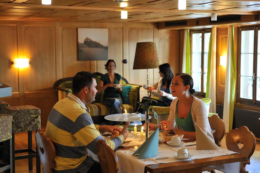 a group of people sitting around a table in a room at Hotel Engelberg "mein Trail Hotel" in Engelberg