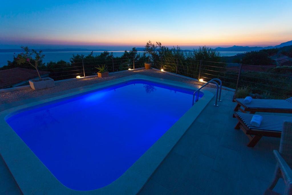 a blue swimming pool with a view of the sunset at Villa Mia Stella in Podgora