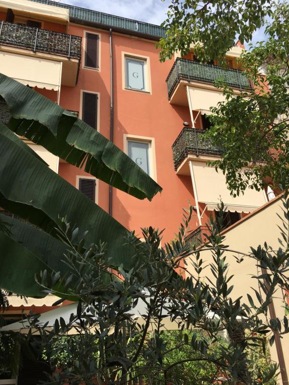 un bâtiment orange et blanc avec des arbres devant lui dans l'établissement Residence Gloria, à Montecatini Terme