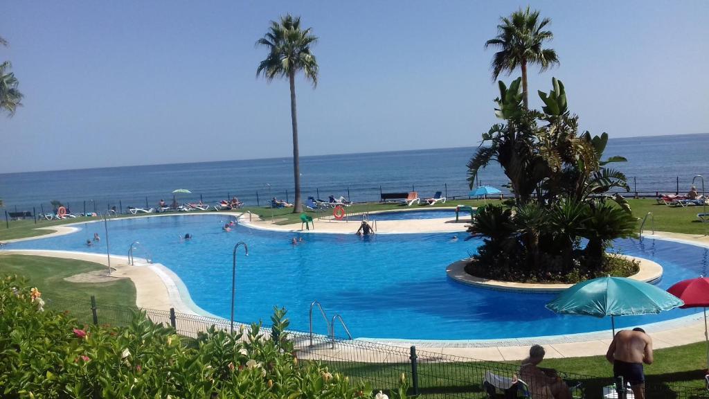 a large swimming pool with palm trees and the ocean at Mi Capricho in Sitio de Calahonda
