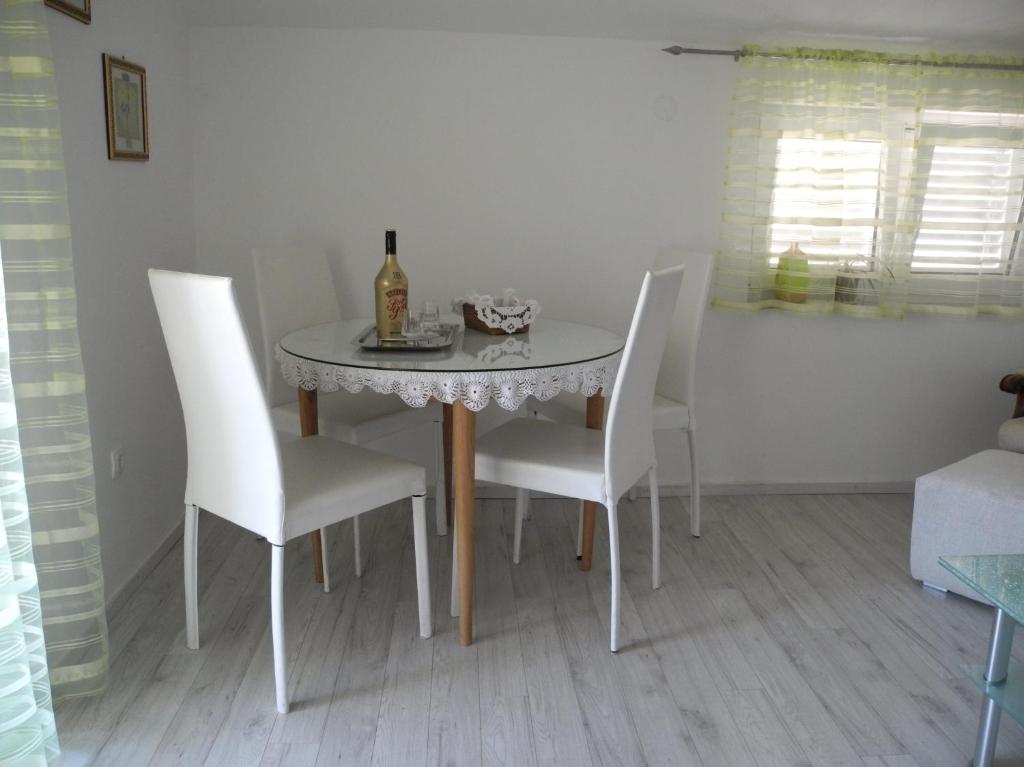 a dining room table with white chairs and a bottle of wine at Villa Ines in Jezera
