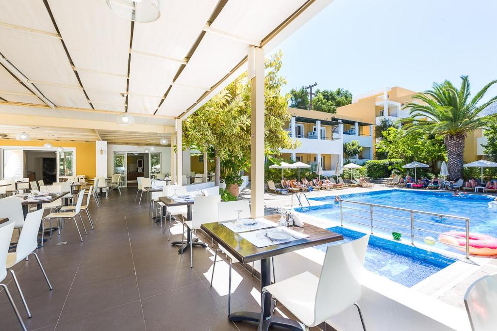 an outdoor dining area with tables and chairs and a swimming pool at Xidas Garden in Bali