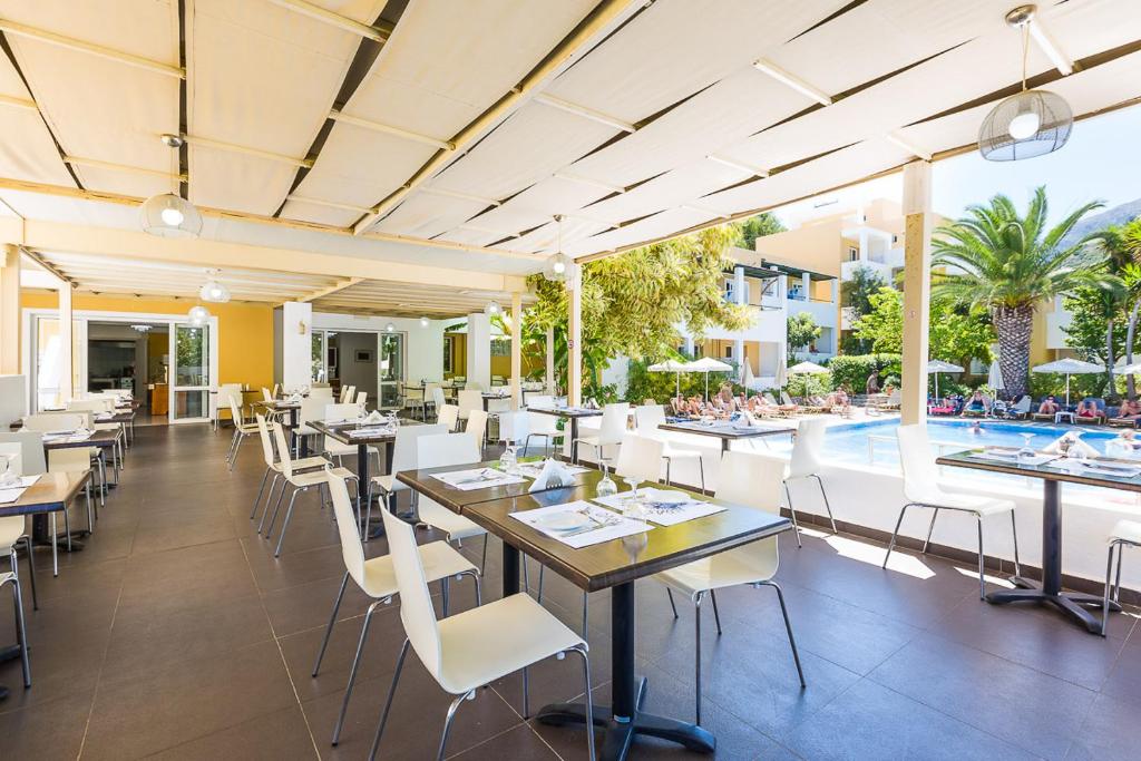a restaurant with tables and chairs and a swimming pool at Xidas Garden in Bali