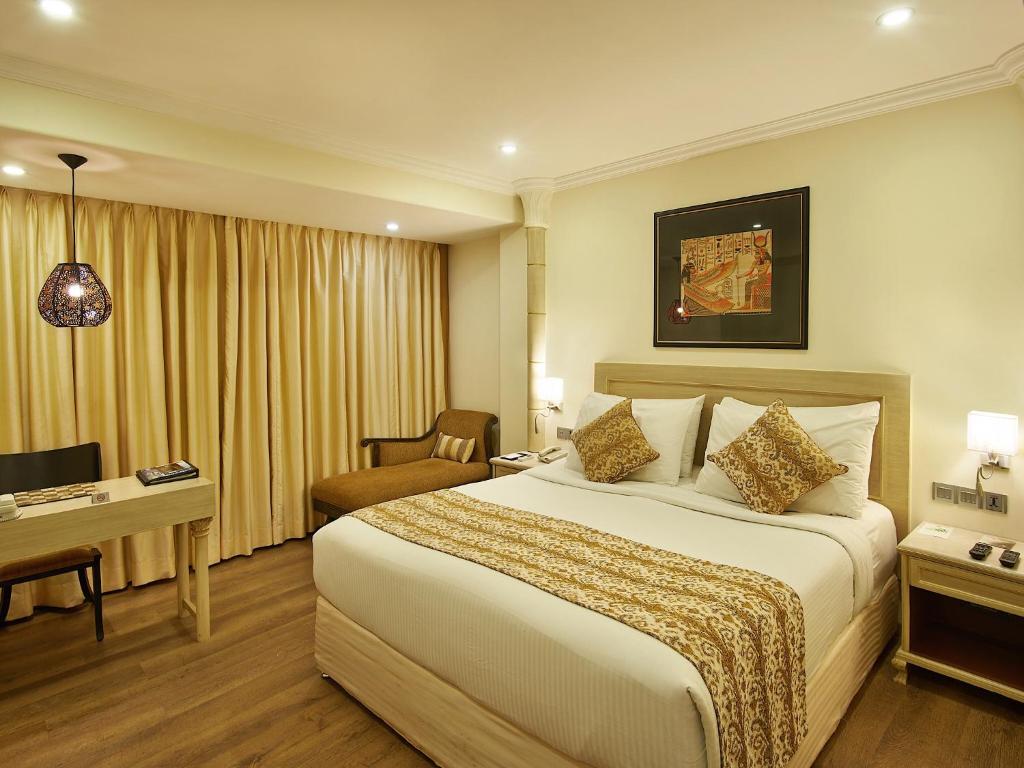 a hotel room with a large bed and a desk at The Shalimar Hotel, Kemps Corner in Mumbai