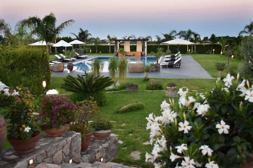 un jardín con flores blancas y una piscina en Villa Fenice, en Calatabiano