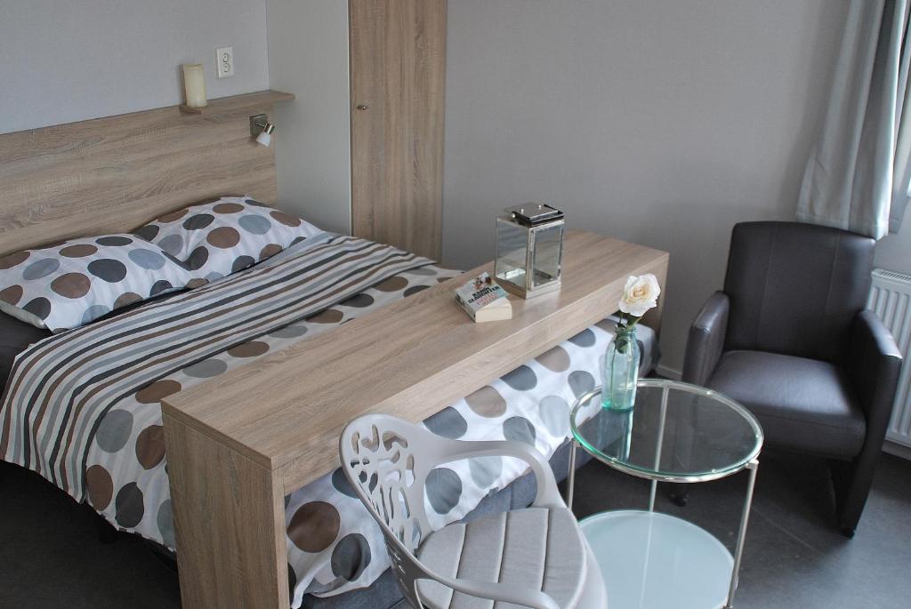 a bedroom with a bed and a table and a chair at Hotel Chalets Middelburg in Middelburg