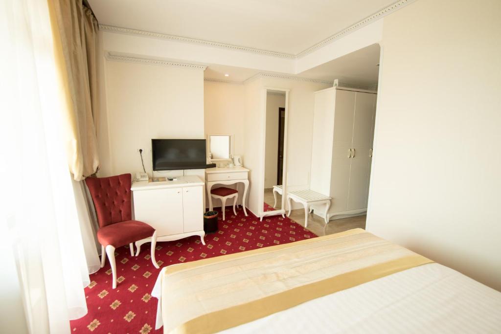 a hotel room with a bed and a desk and a television at MSR Port Hotel in Mangalia