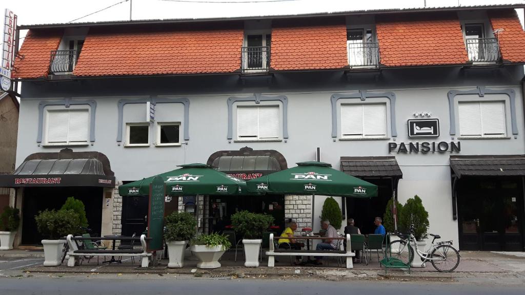 a restaurant with green umbrellas in front of a building at RESTORAN PRENOĆIŠTE CROATIA TURIST in Đakovo