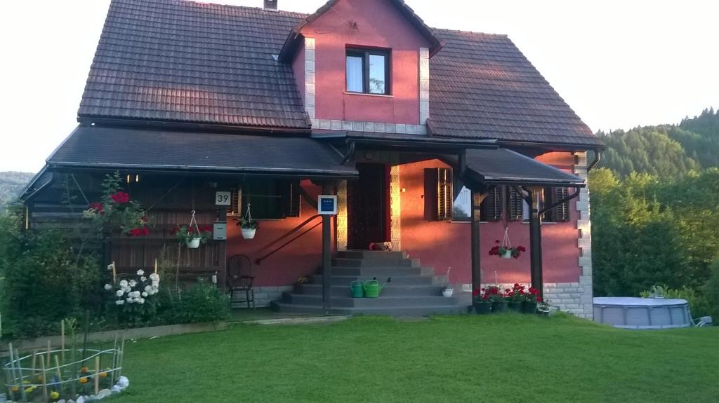 una casa roja con un patio verde delante de ella en Apartman Anika, en Moravice