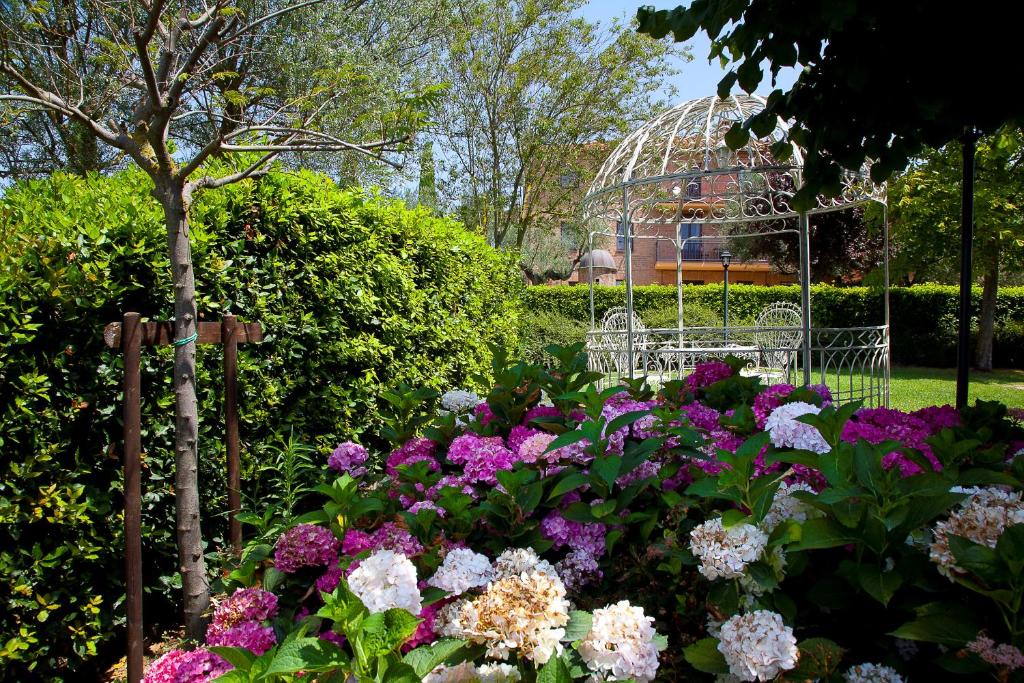 a garden with flowers and a gazebo in the background at Borgo Tre Rose in Valiano