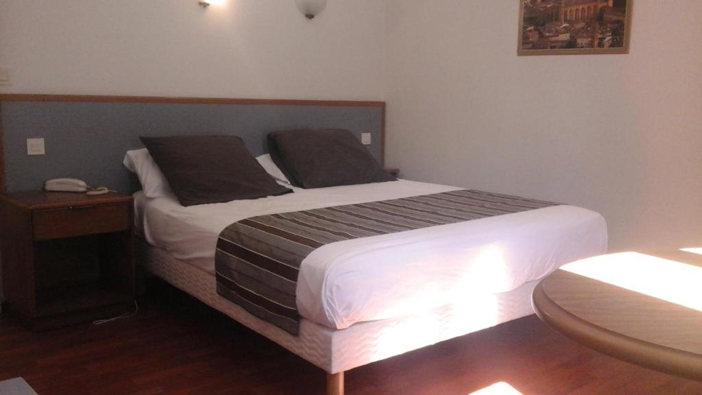 a bedroom with a large bed with a night stand and a phone at Hotel Boreal in Toulouse