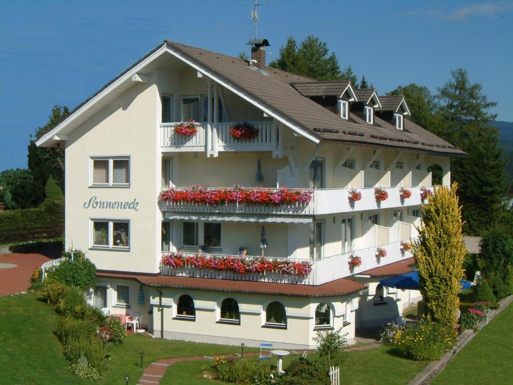 ein großes weißes Gebäude mit Blumen auf den Balkonen in der Unterkunft Pension Sonneneck in Bayerisch Eisenstein
