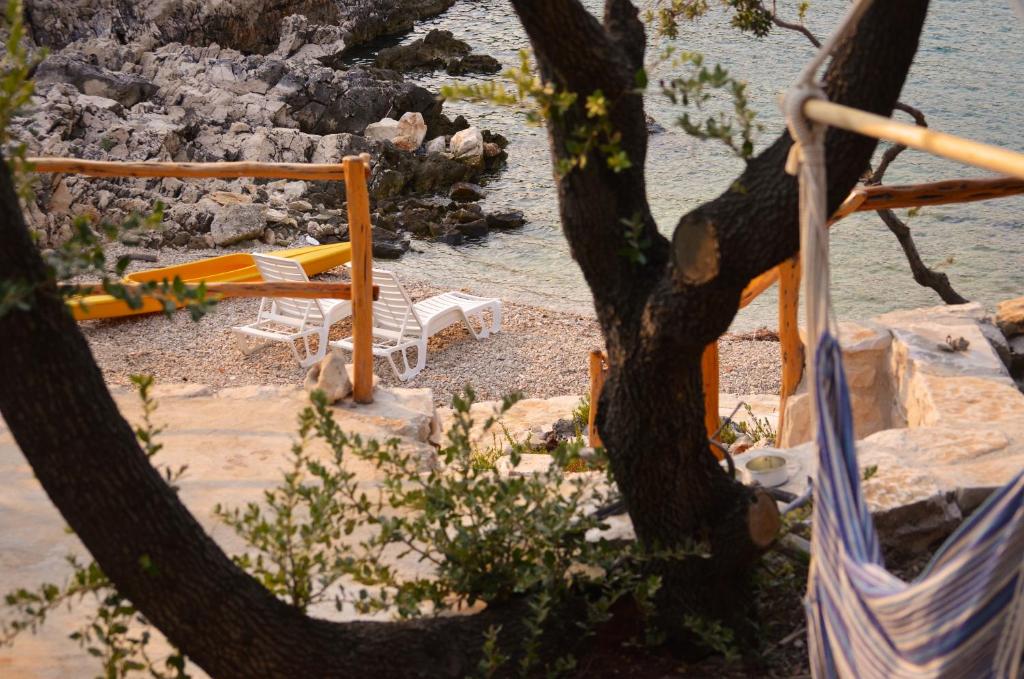 a view of a beach with chairs and a tree at Holiday House Trovna in Pučišća