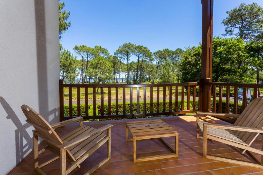 two chairs and a table on a porch with a fence at Duplex T3 2 étoiles bord de lac 65mcarrés in Biscarrosse
