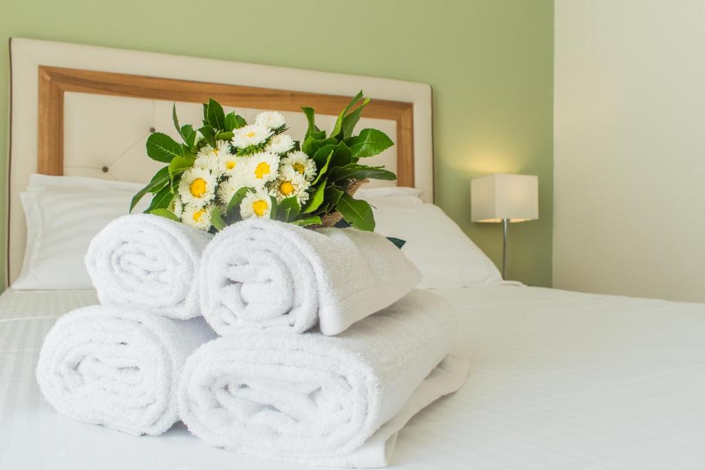 a pile of towels on a bed with a bouquet of flowers at Castello Boutique Rooms in Kavála