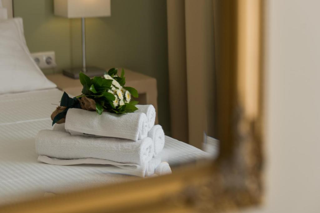 a stack of towels on a bed with a mirror at Castello Boutique Rooms in Kavála