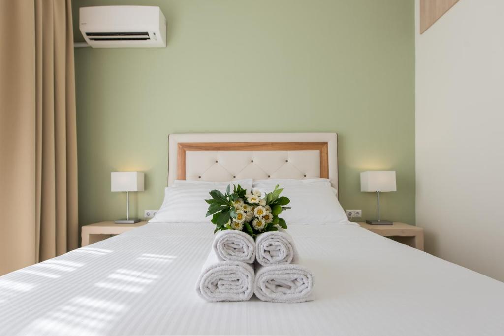 a bedroom with a white bed with flowers and towels at Castello Boutique Rooms in Kavála