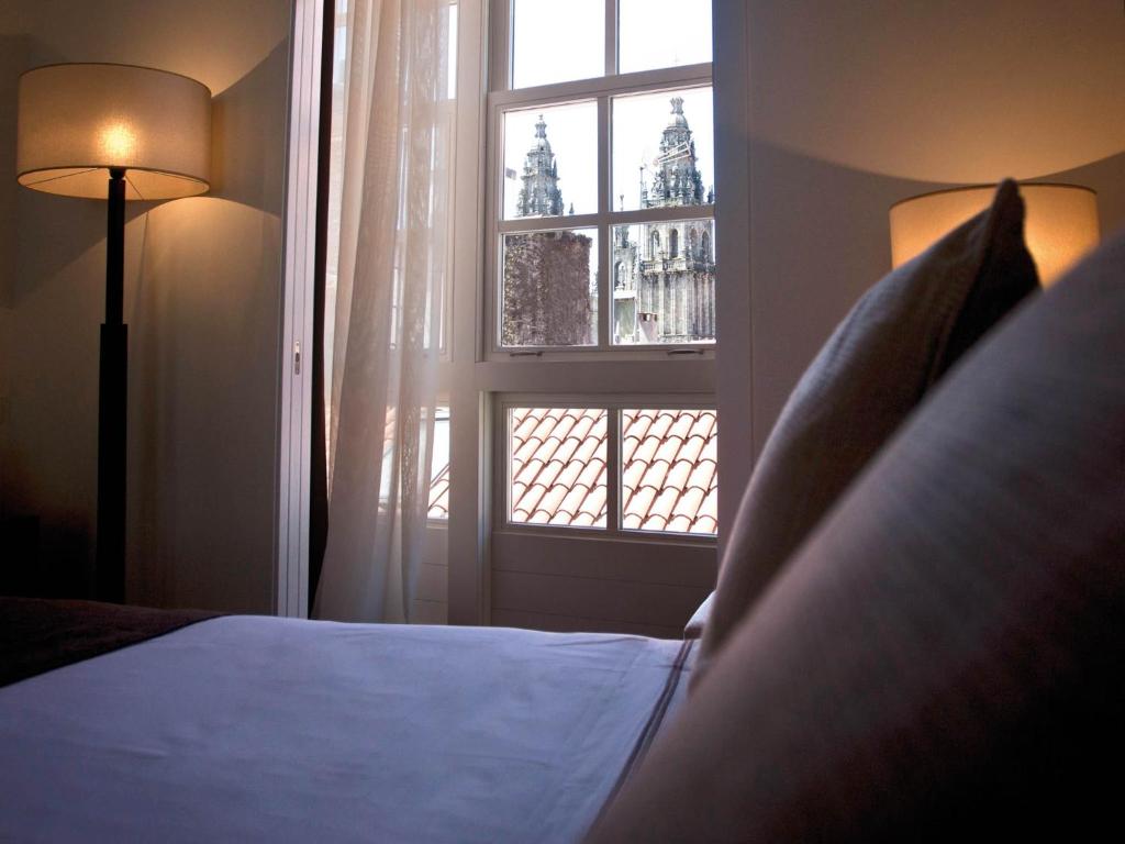 a bedroom with a bed and a window at Carris Casa de la Troya in Santiago de Compostela