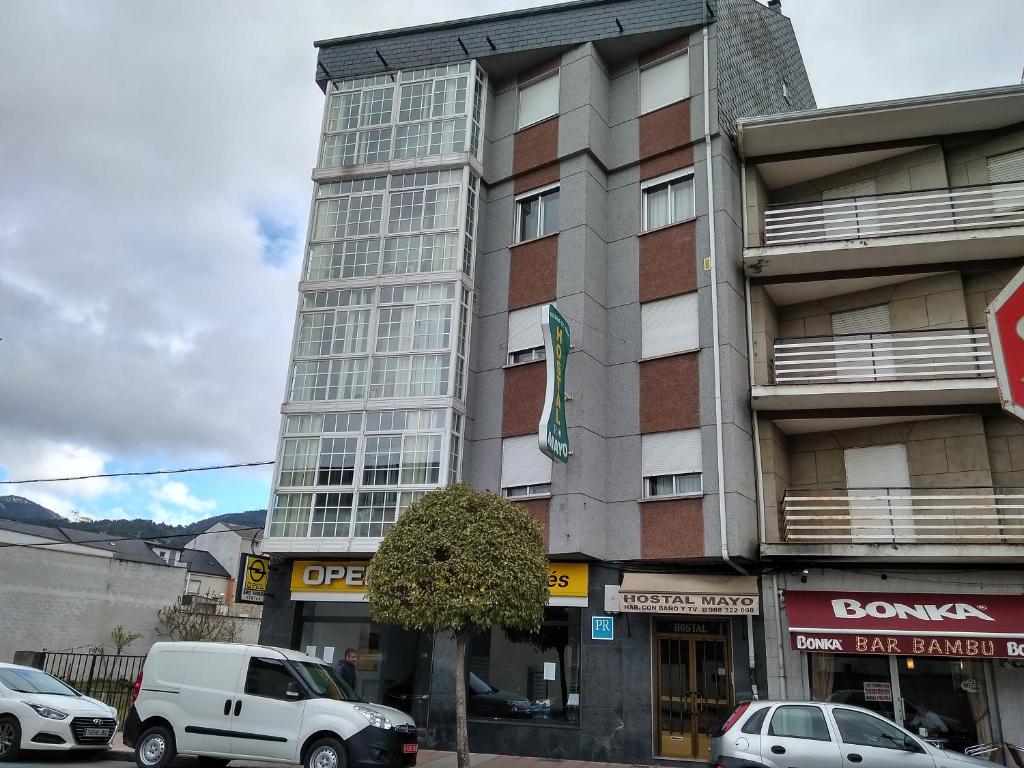 un edificio alto con coches estacionados frente a él en Hostal Mayo, en O Barco de Valdeorras