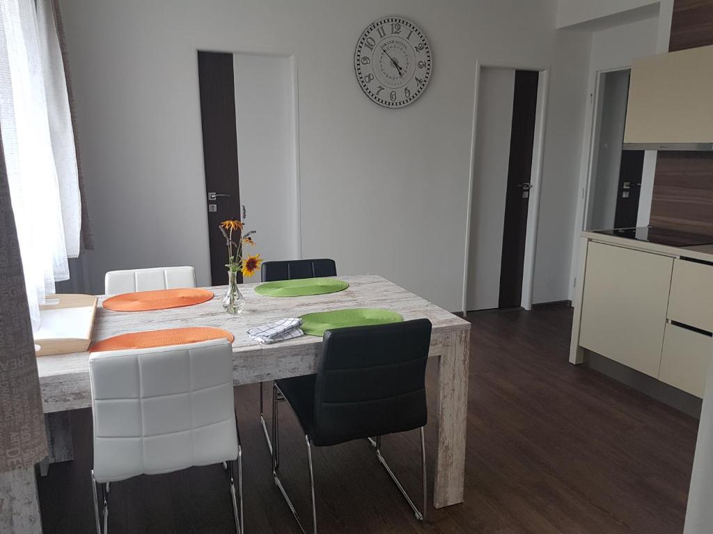 eine Küche mit einem Tisch mit Stühlen und einer Uhr an der Wand in der Unterkunft Apartmány u skanzenu in Rožnov pod Radhoštěm