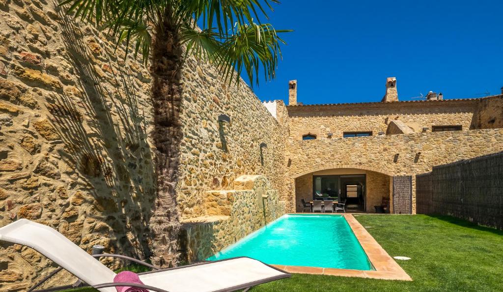 a villa with a swimming pool next to a stone wall at Can Caranta in Pals