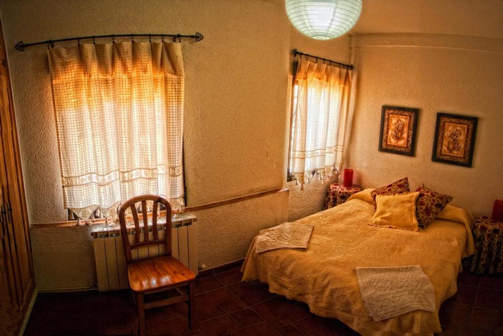 アレーナス・デ・サン・ペドロにあるLos Sotillos De Gredosのベッドルーム1室(ベッド1台、椅子、窓付)