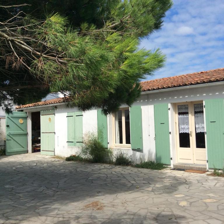 un bâtiment avec des portes vertes et blanches et un arbre dans l'établissement Maison Ile de Re, à La Couarde-sur-Mer