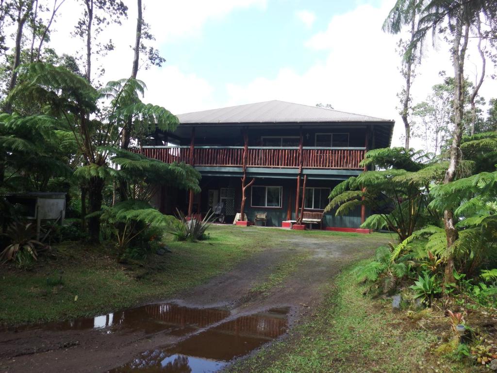 a house in the middle of a forest with a driveway at Aloha Crater Lodge in Volcano