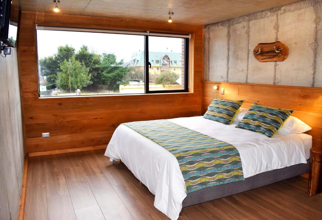 a bedroom with a bed and a large window at Hotel Amun in Villarrica