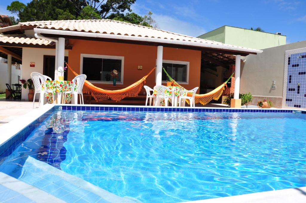una piscina con sillas y una casa en Recanto do Village, en Porto Seguro
