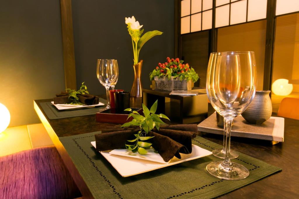 a table with two wine glasses and plants on it at Hosta Nijo Aoi in Kyoto