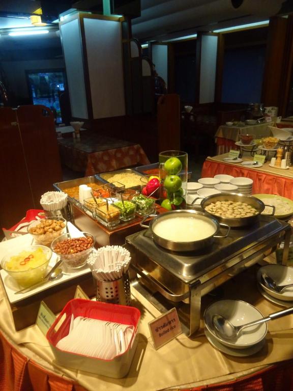 A close-up buffet station with hot dishes, sauces, fruit and serving ware.