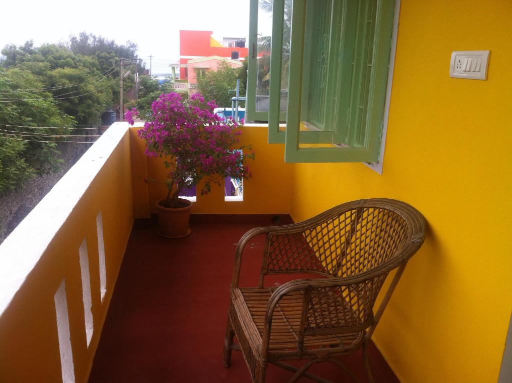 een rieten stoel op een balkon met een raam bij Blue Moon Guest House in Mahabalipuram
