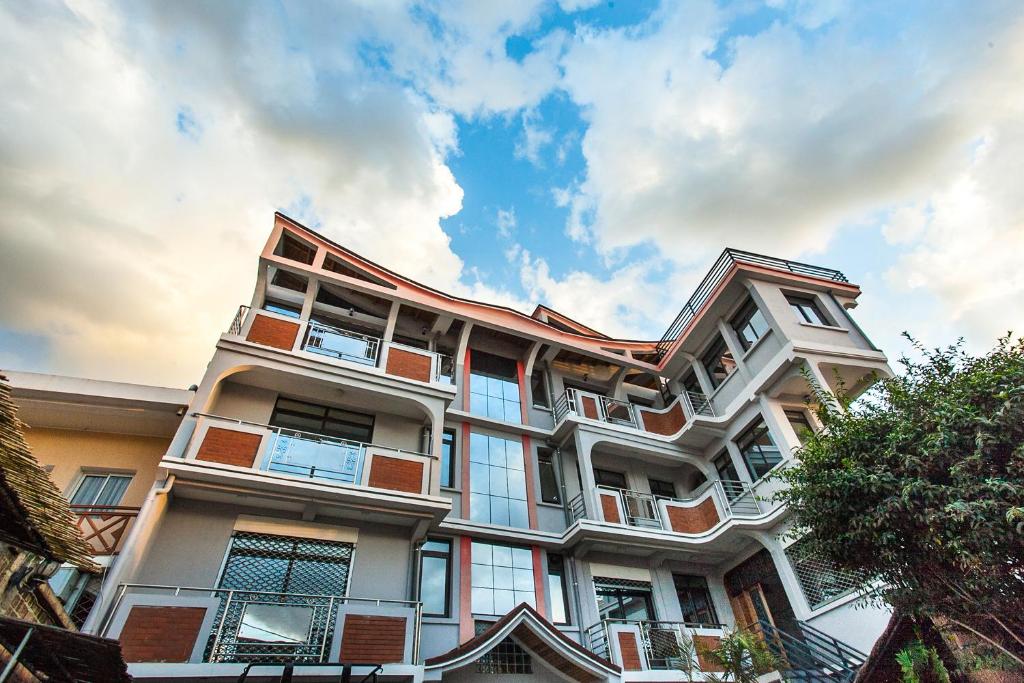 a tall white building with windows and a cloudy sky at OCEANIS HOME & VOYAGES in Ivato