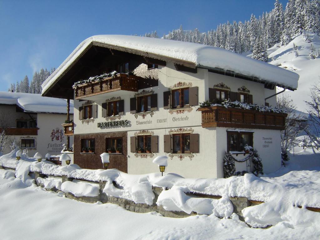 un edificio cubierto de nieve frente a una montaña en Pension Hartenfels, en Lech am Arlberg