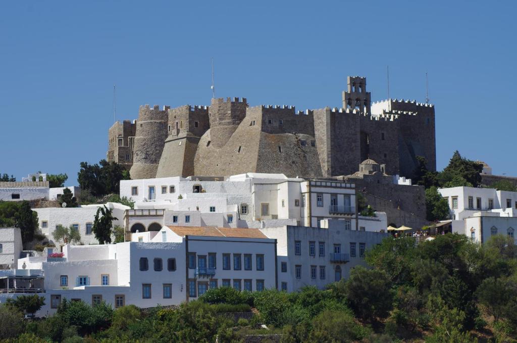een groep witte gebouwen met een kasteel op de achtergrond bij Effie Hotel in Skala