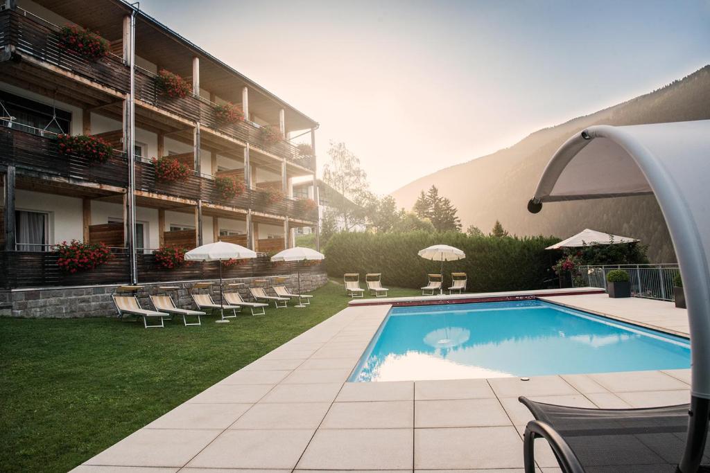 un hotel con piscina accanto a un edificio di Kreativ Hotel Landhaus Schweigl a Ultimo