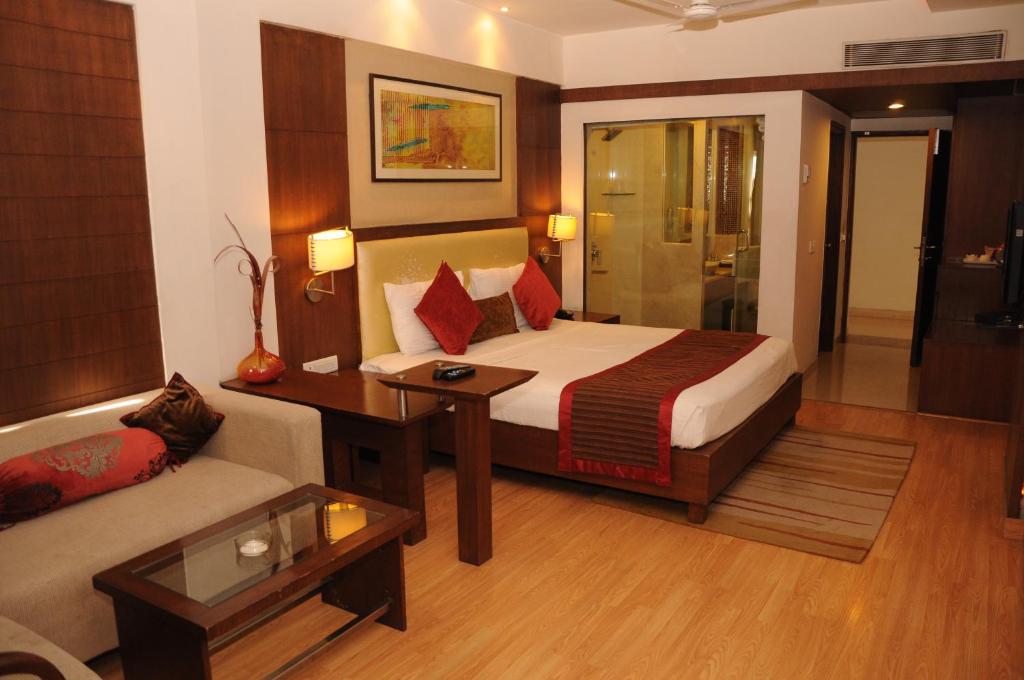 グワーリヤルにあるHotel Gwalior Regencyのベッドとソファ付きのホテルルーム