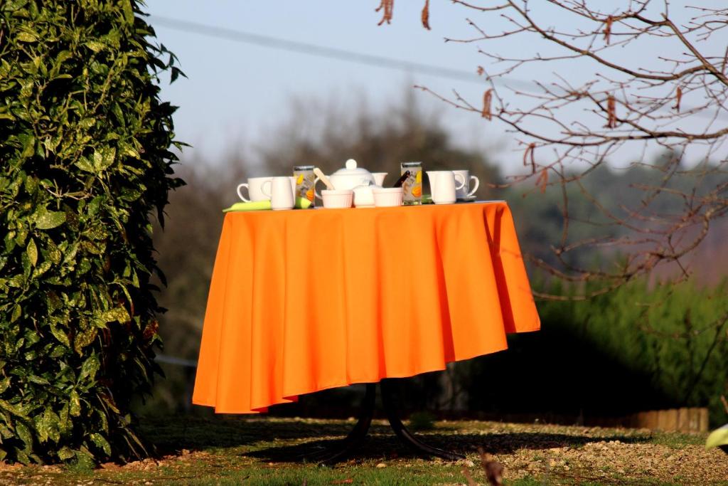 una mesa naranja con tazas y tazas. en Chez Annie en Saint-Avit-Rivière
