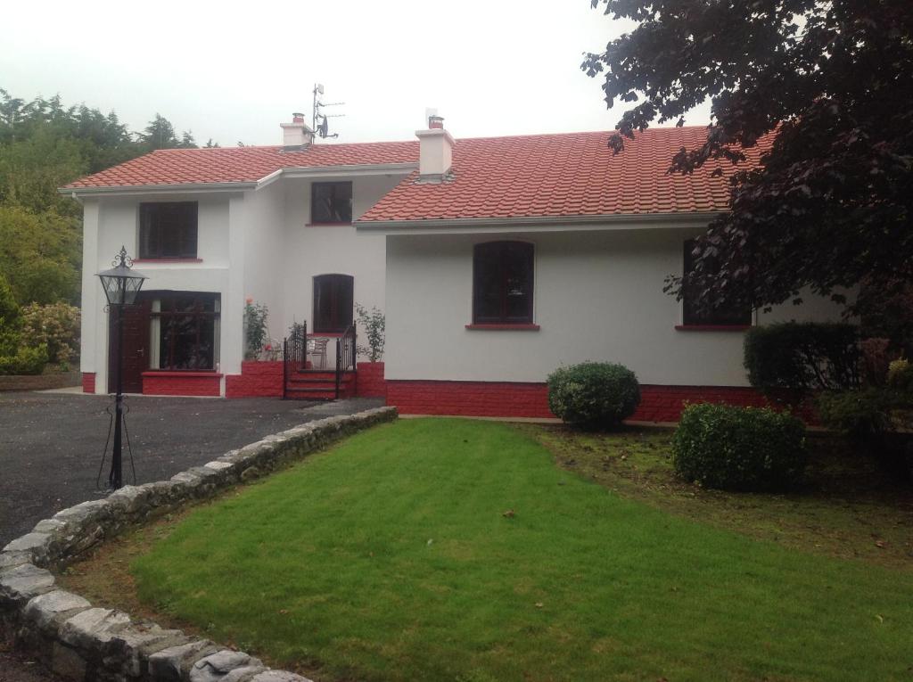 Casa blanca con techo rojo y patio en Beech Lodge B&B, en Lisheenanoran